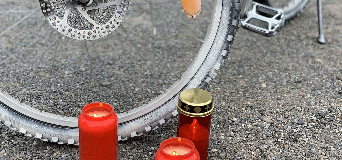 Ein weißes Ghostbike und brennende Kerzen. Ein weißes Ghostbike und brennende Kerzen.